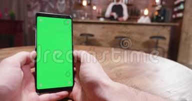 在一家老式<strong>酒吧</strong>里用绿色屏幕智能手机拍摄的手持<strong>照片</strong>